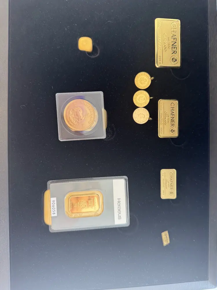 Sammlung mit Goldmünzen und Goldbarren verschiedener Hersteller in einer dunklen Schatulle